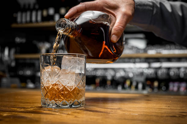 man's hand pouring whisky into glass - action alcohol alcoholism bar imagens e fotografias de stock