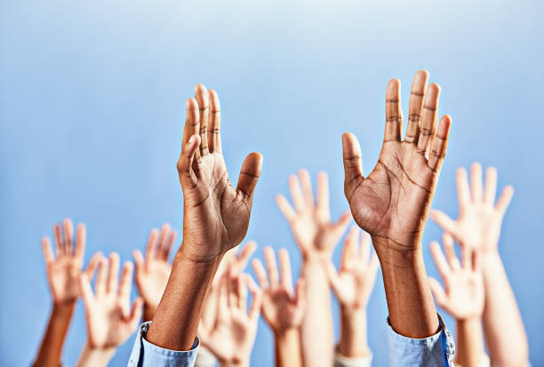 Many hands raised to heaven, praying or worshiping Group of open human hands being held aloft. revival stock pictures, royalty-free photos & images