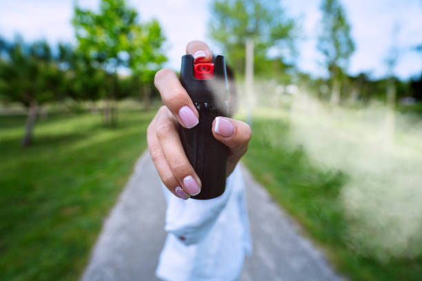 mujer usando gas pimienta o gases lacrimógenos para autodefensa al aire libre - pulverizador de pimienta fotografías e imágenes de stock