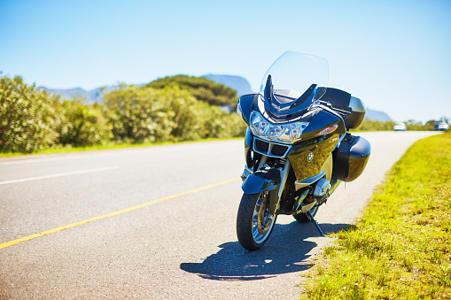 Cape Town, South Africa - September 16, 2011: A large luxury touring motorcycle, a BMW R1200RT, stands parked beside a two-lane road in the countryside near Cape Town.