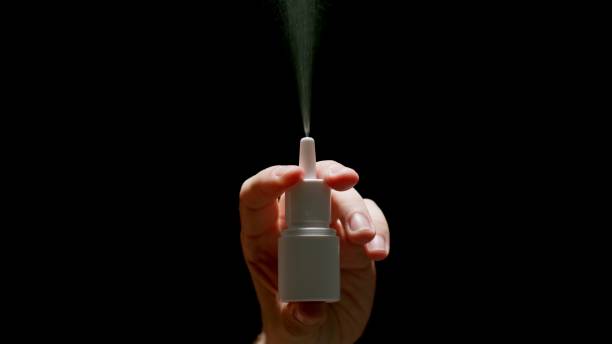 istock Human Hand Sprays Nasal Spray From a Dispenser on a black background 1314008435