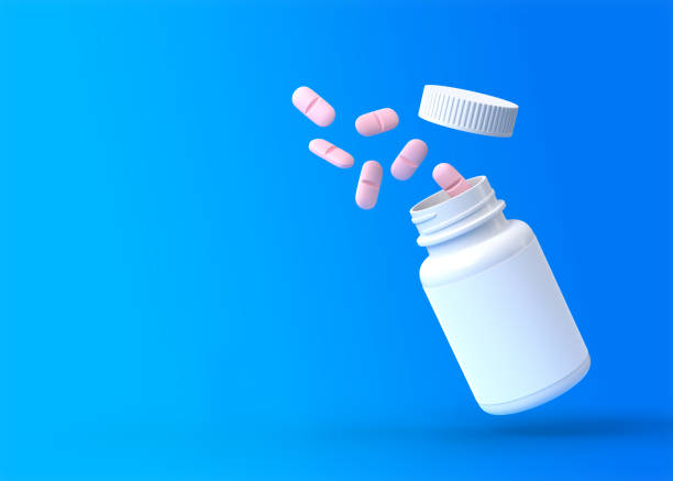 istock Falling pink pills are spilling from the white pharmacy bottle on a blue background 1314010920