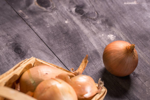 istock Brown onions in basket on wooden background. 1314013571