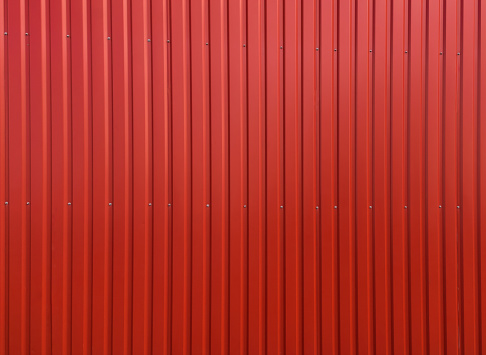 Background and texture. Modern building material. Red bright aluminum sidin, painted with paint. Wall covering for office buildings and warehouses