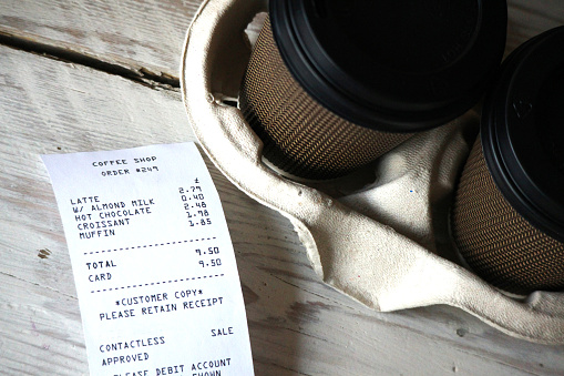 A fictional receipt next to takeaway coffee cups.