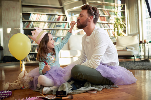 Excited father and daughter playing together in the living room