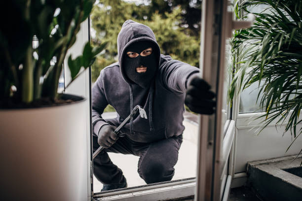 Robber breaking in house One man, criminal dressed all in black with crowbar, breaking in through window in house. thief stock pictures, royalty-free photos & images