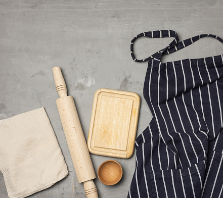 blue striped chef apron, wooden utensils on gray background, top view