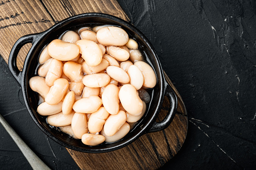 White canned beans set, in bowl, on black stone background, top view flat lay, with copy space for text