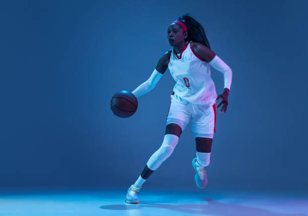 schöne afrikanisch-amerikanische basketballspielerin in bewegung und aktion in neonlicht auf blauem hintergrund. konzept von gesundem lebensstil, profisport, hobby. - stroboscopic image stock-fotos und bilder