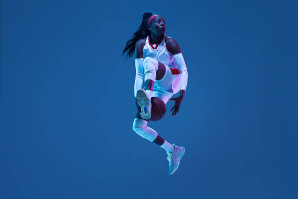piękna afroamerykańska koszykarka w ruchu i akcji w neonowym świetle na niebieskim tle. koncepcja zdrowego stylu życia, sportu zawodowego, hobby. - basketball playing ball african descent zdjęcia i obrazy z banku zdjęć