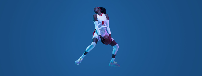 Flyer. Beautiful african-american female basketball player in motion and action in neon light on blue background. Concept of healthy lifestyle, professional sport, hobby. Woman in sport.