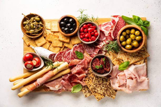 Appetizers with differents antipasti Appetizers with differents antipasti, charcuterie, snacks and red wine on white background. Sausage, ham, tapas, olives and crackers for buffet party. Top view, flat lay charcuterie stock pictures, royalty-free photos & images