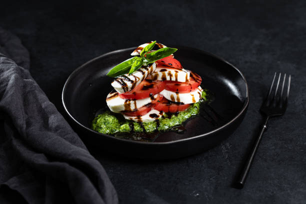 insalata caprese su sfondo nero - mozzarella tomato antipasto appetizer foto e immagini stock