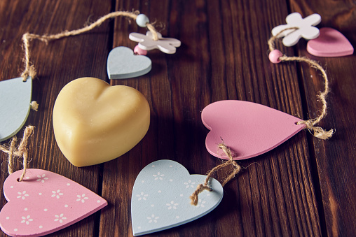 A fragrant organic handmade soap in the shape of a heart with wooden decor on a dark background.