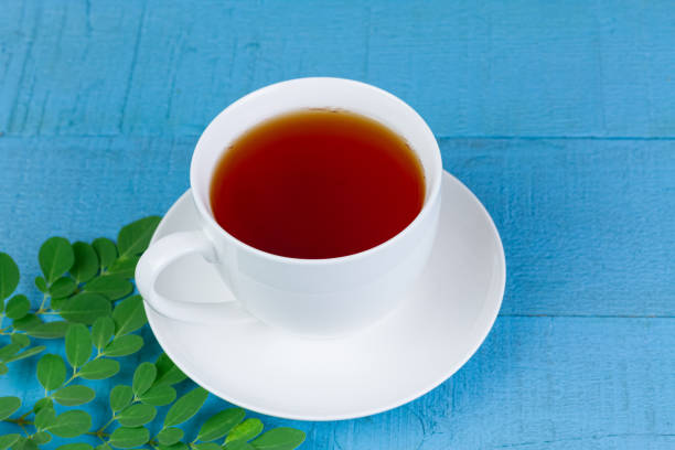 istock moringa tea in white ceramic cup and fresh green moringa leaf on blue wooden background. 1314035377