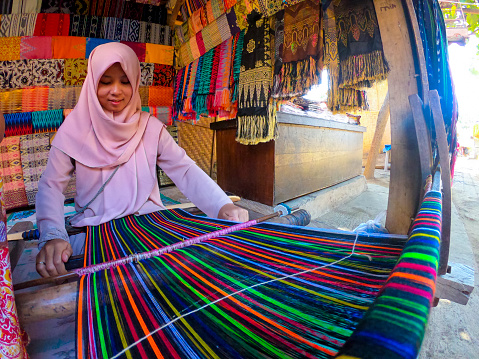 Lombok Indonesia, August 6 2019 : Sasak lady traditionally makes yarn with a spindle wheel at traditional Sasak village, Desa Sasak Sade, Lombok Indonesia
