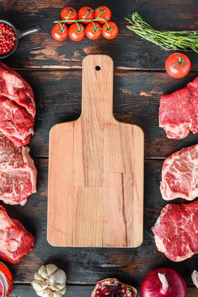 istock Meat beef steaks frame concept, with different steak cuts andempty chopping board  in frame on dark old wooden table  top view 1314038204
