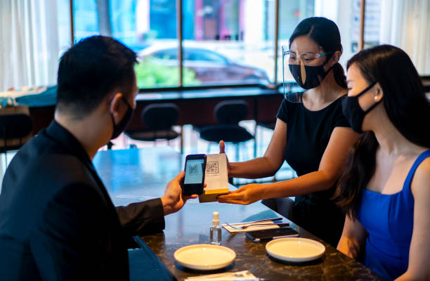 istock Asian waitress with face mask and face shield asking customer to scan QR code for food menu. 1314038300