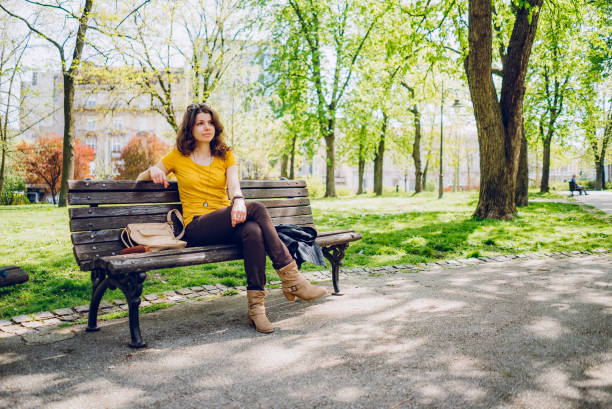 istock Young caucasian woman sitting on a park bench 1314041909