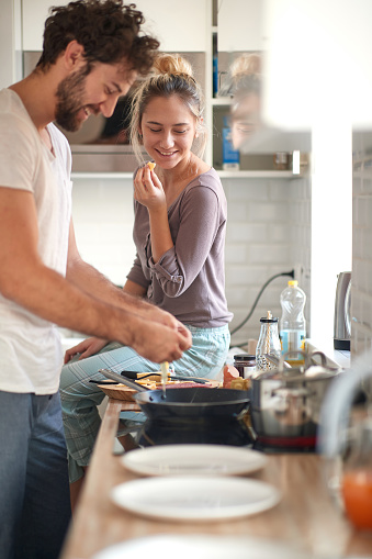 A young girl likes when her boyfriend preparing the food in a home atmosphere. Cooking, home, kitchen, relationship