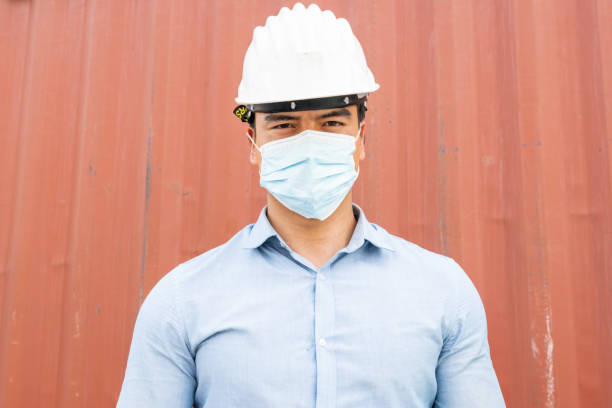 istock Portrait of logistic engineer worker man wear protective mask looking at camera. working during Coronavirus epidemic at container warehouse construction site. 1314043661