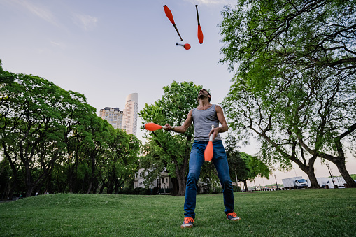 Argentinian mature man juggling with cones in public park. Puerto Madero, Buenos Aires, Argentina.