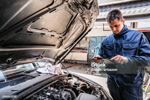 Mechanic Examining Car Diagnostics On Digital Tablet Stock Photo - Download Image Now