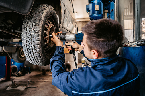 Auto mechanic changes a tire on car in a repair shop.