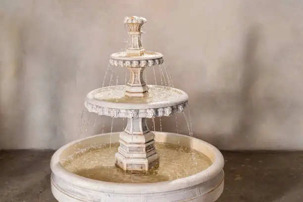 Photo of vintage stone multi-tiered fountain with pouring water in interior