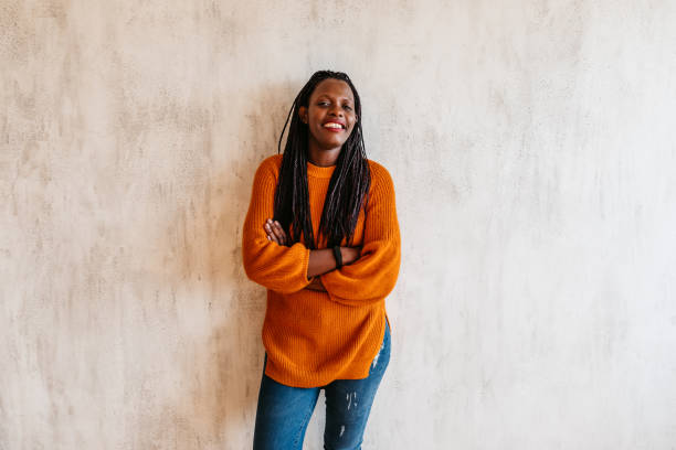 Happy young black woman laughing against wall
