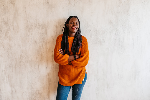 Portrait of happy young black woman laughing against wall.