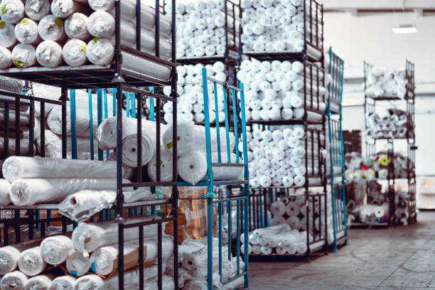 Male Wearhouse Worker Smiling While Carrying Rolled Cloth Pieces