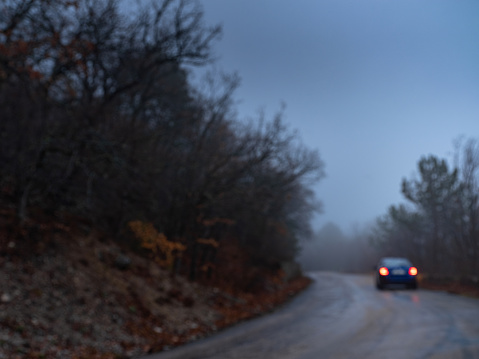 blue car headlight beams in dense mist. Driving in the Fog on the mountain road in the forest.