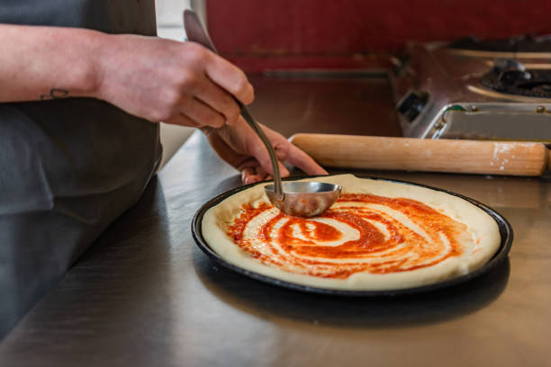 istock Close-up of chef using ladle to spread sauce on a pizza 1314058462