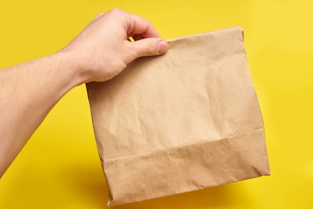 istock Man hand hold brown clear empty blank craft paper bag 1314059178