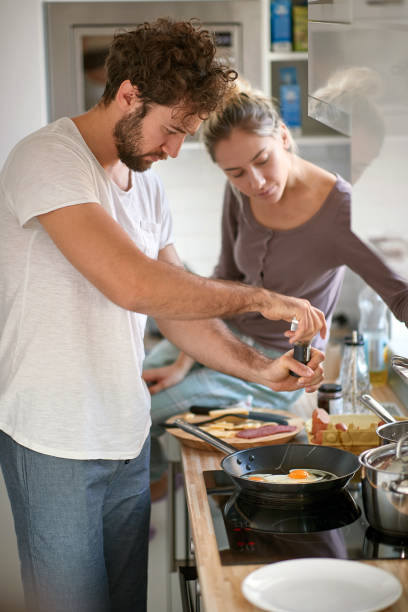 istock young caucasian beardy guy with curly hair making breakfast, while his female partner observing 1314059215