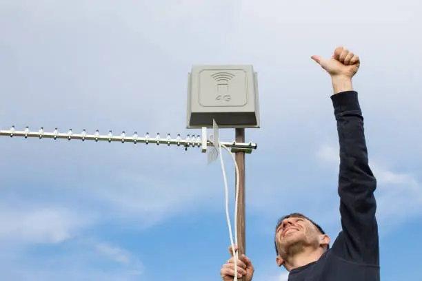 Photo of Man install antenna and showing thumb up. Good 4G signal. Installing 4G antennas in cottage