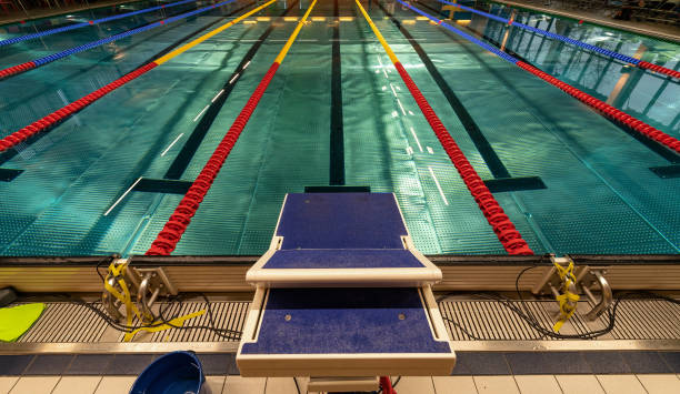 istock Perspective view at starting platform and quiet swimming pool with multicolored lane lines, no people scene 1314065052
