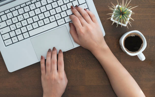 istock female hands are using laptop computer. working on wooden table, top view 1314065552