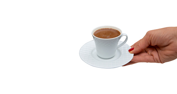 Woman's hand holding Turkish coffee cup in front of isolated background