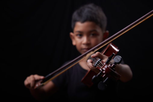 Young boy play the violin on black background