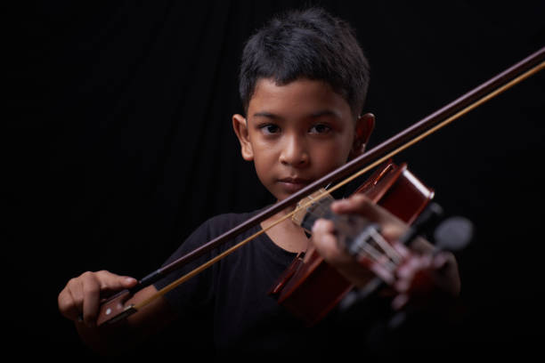 Young boy play the violin on black background stock photo