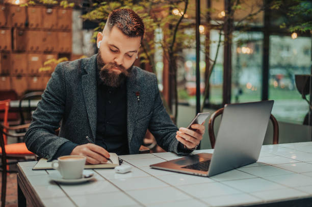 istock Businessman using a smartphone and a laptop in a coffee shop 1314073785