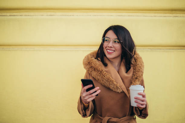istock Hispanic woman using a smartphone and a coffee takeaway 1314073873