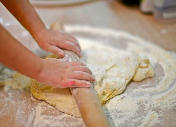 istock Little girl kneads dough for baking. 1314073928