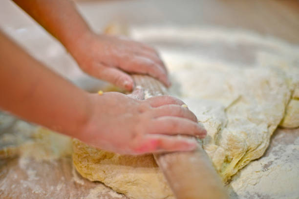 istock Little girl kneads dough for baking. 1314074020
