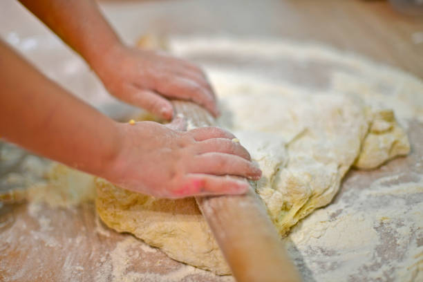 istock Little girl kneads dough for baking. 1314074114