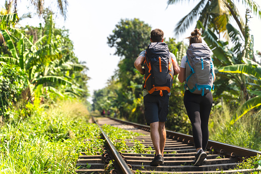 walking on a railroad in a tropical location. young couple with big backpack. Sri lanka