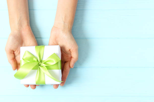 istock gift in female hands on a colored background top view. 1314077950